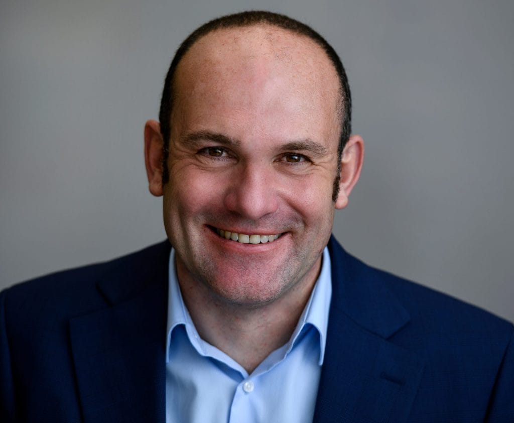 A man in a blue suit smiling for the camera.