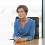 A professional woman sitting at a conference table, appearing attentive.